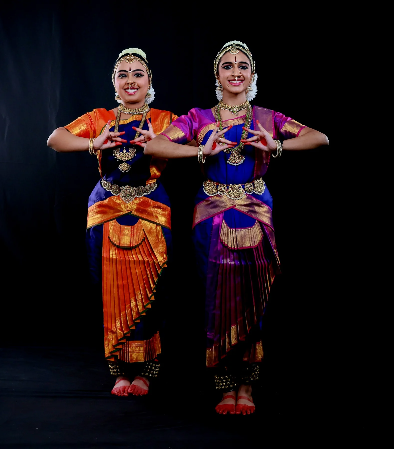 Shreya and Shriya standing together with hands forming a symmetrical mudra offering