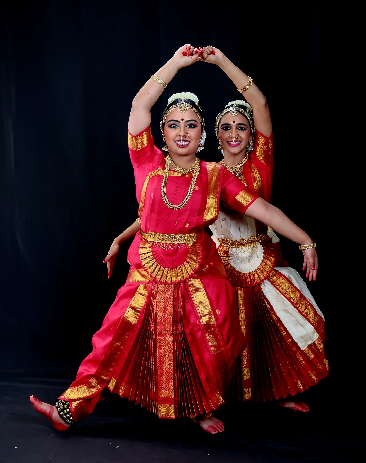 Shreya and Shriya close together, one dancer framed by the other's overhead arms for the Amritavarshini